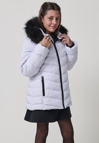 Chaqueta de plumón gris claro con capucha de piel sintética negra, cremallera frontal y dos bolsillos laterales en ángulo; textura acolchada en toda la prenda.