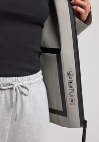 Veste imperméable grise avec intérieur noir, dotée d'une fermeture éclair, de symboles imprimés indiquant résistance au vent, imperméabilité, coutures chauffées et capuche fixe.