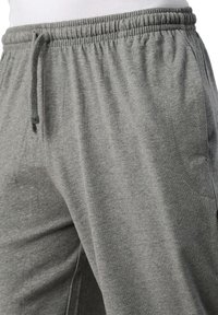 Graue Jogginghosen aus weichem Stoff, mit einem elastischen Bund und Kordelzug, seitlichen Taschen und einfachen Nähdetails.