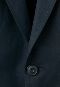 Dunkelblaues Marineblazer mit Kerbkragen und einem einzelnen schwarzen Knopf, der vorne geschlossen ist.