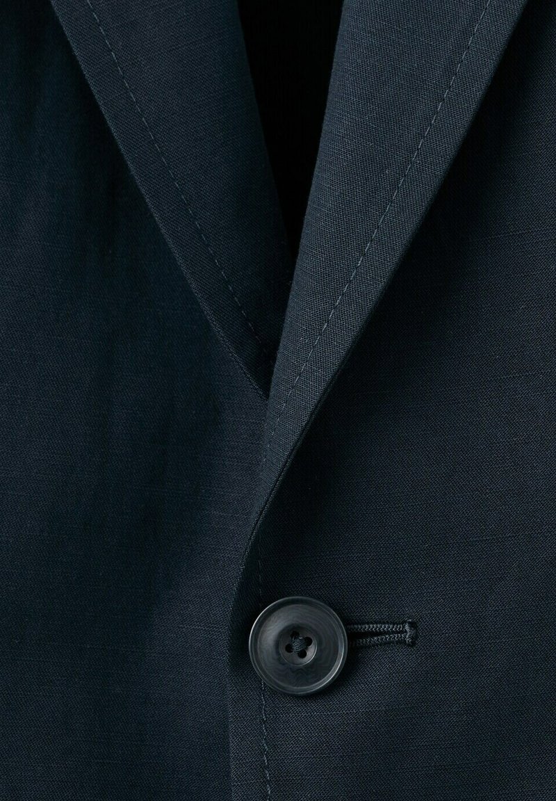 Blazer azul marino oscuro con solapa de muesca y un solo botón negro abrochado al frente.