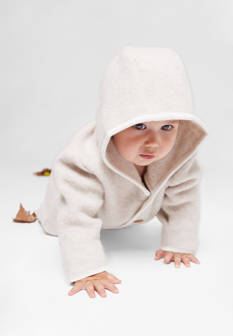 Cappotto in lana beige chiaro con cappuccio, dotato di chiusura a bottone e bordature bianche. Tessuto morbido, adatto per neonati che gattonano.