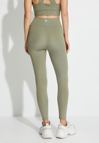 Leggings atléticos de cintura alta en verde oliva, fabricados con un material suave y elástico. Diseño ajustado con un mínimo de marca en la cintura.