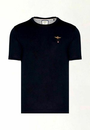 T-shirt nero a maniche corte realizzato in cotone. Presenta un piccolo emblema dorato di un'aquila con le iniziali "A.M." e un accento circolare rosso sul petto.