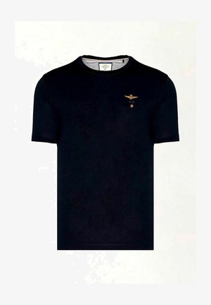 T-shirt nero a maniche corte realizzato in cotone. Presenta un piccolo emblema dorato di un'aquila con le iniziali "A.M." e un accento circolare rosso sul petto.