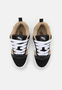 Zapatillas negras y marrones con cordones blancos, materiales de ante y lona, forma de punta redonda y marca en la lengüeta. Suela de goma y tirador.