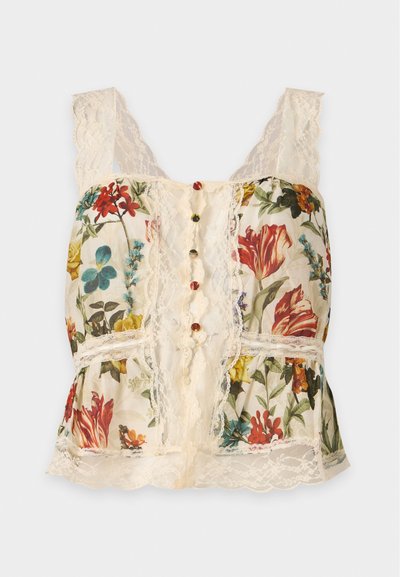 Haut sans manches crème orné de dentelle avec imprimé floral multicolore et rangée de boutons décoratifs sur le devant, sur fond uni clair.