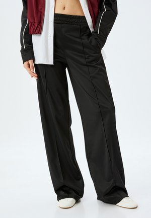 Schwarze weit geschnittene Hose aus glattem, mattem Material; mit einem elastischen Bund und klaren Linien für einen maßgeschneiderten Look.