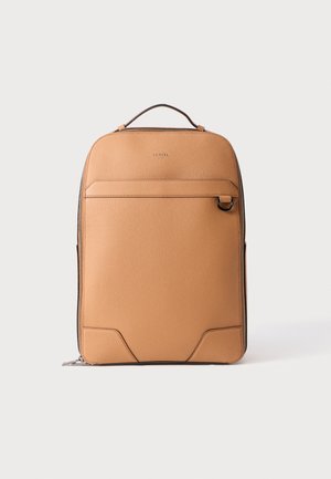 Tan-värinen nahkareppu, jossa on sileä pinta, suorakulmainen muoto, yläkahva, etupuolen vetoketjullinen tasku ja tummanruskeat yksityiskohdat. Lancel-logo edessä.