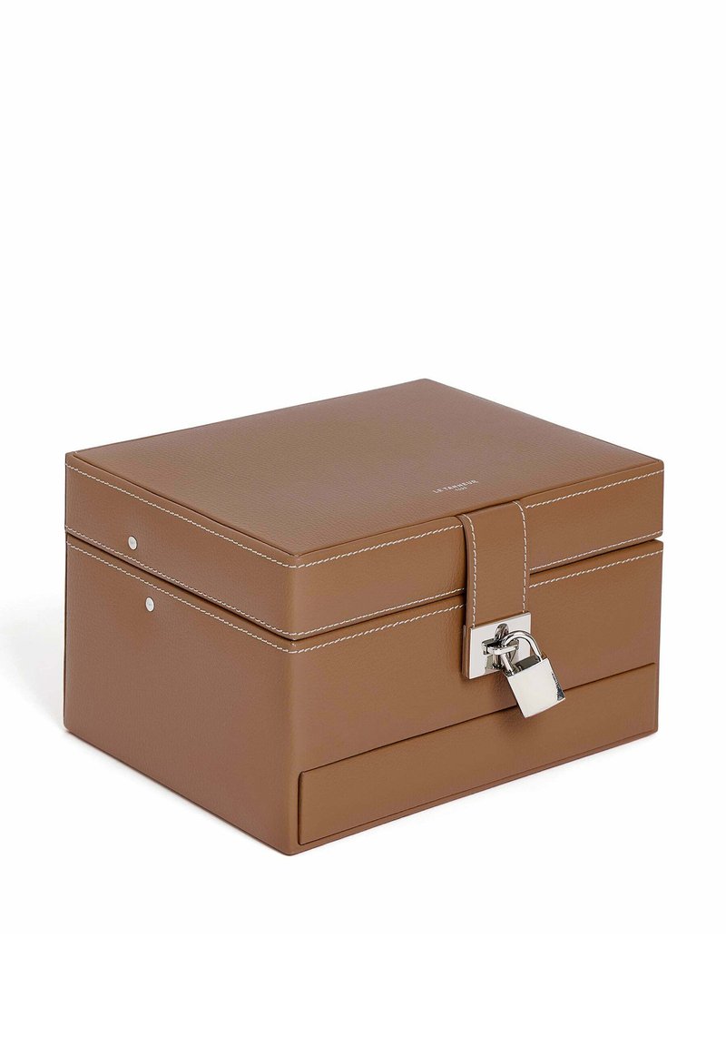 Scatola di immagazzinaggio in pelle marrone con hardware argentato, un lucchetto e cuciture bianche. Forma rettangolare con una superficie liscia e design minimalista.