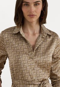 Geprinte overhemd met knopen in beige en goudtinten, voorzien van een geometrisch patroon, een klassieke kraag, lange mouwen en een strikdetail in de taille.