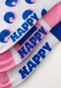 Tres pares de calcetines con una base blanca, texto en azul que dice "HAPPY", acentos en rosa y un patrón en espiral de colores azul y rosa.