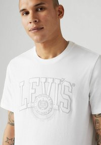 Vit bomull t-shirt med en upphöjd, tonad Levi's-logotyp och emblem. Rund halsringning, korta ärmar och en mjuk textur.