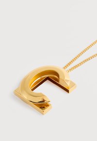 Κολιέ σε χρυσό τόνο με κυκλικό μενταγιόν που διαθέτει ασύμμετρο άνοιγμα και λεία, γυαλιστερή επιφάνεια σε μια λεπτή αλυσίδα.