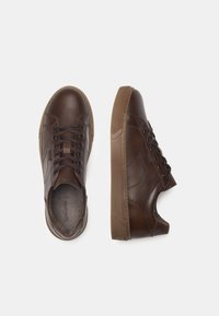 Sneakers in pelle marrone con punta rotonda, chiusura con lacci, suole in gomma e texture liscia. Presentano cuciture sottili e un design a basso profilo.