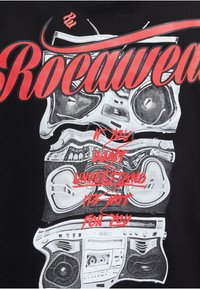 Black t-shirt featuring a graphic print of vintage boomboxes and the word "Rocawear" in bold red letters with additional red text underneath.