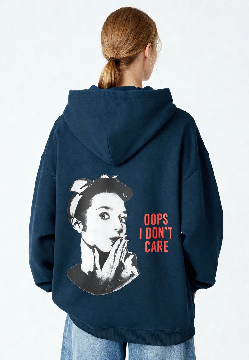 Felpa con cappuccio blu navy dalla vestibilità oversize. Presenta una stampa grafica sul retro con il volto di una donna e la scritta "OOPS I DON'T CARE" in rosso.