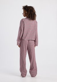 Pajamasetissä on punaiset ja valkoiset ruudut, rento malli, jossa on paita ja yhteensopivat housut, valmistettu pehmeästä puuvillakankaasta.
