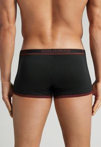 Boxer shorts para hombres negros con un acento burdeos en el dobladillo y la cinturilla, que presentan una textura suave y costuras planas para mayor comodidad.