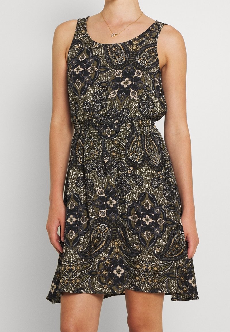 Robe sans manches avec taille élastique présentant un imprimé complexe de motifs paisley et floraux en noir, vert olive et beige.