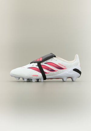 Weißer Adidas Predator Fußballschuh mit rosa Streifen, schwarzer Schnürsenkelabdeckung und geformten Stollen auf neutralem Hintergrund.