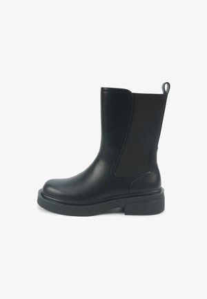 Sort læderankelstøvle med elastiske sidepaneler, rundet tå og tyk gummisål. Trækkeklap bagpå for nem påtagning.