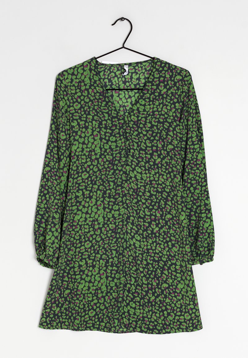 Robe à motifs verts et noirs avec un décolleté en V, de longues manches bouffantes et un ourlet évasé. Présente un imprimé texturé à pois de tailles variées.