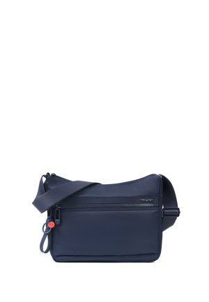 Compact navy blue crossbody bag with adjustable strap and front zip pocket, featuring a small red charm near the zipper pull.