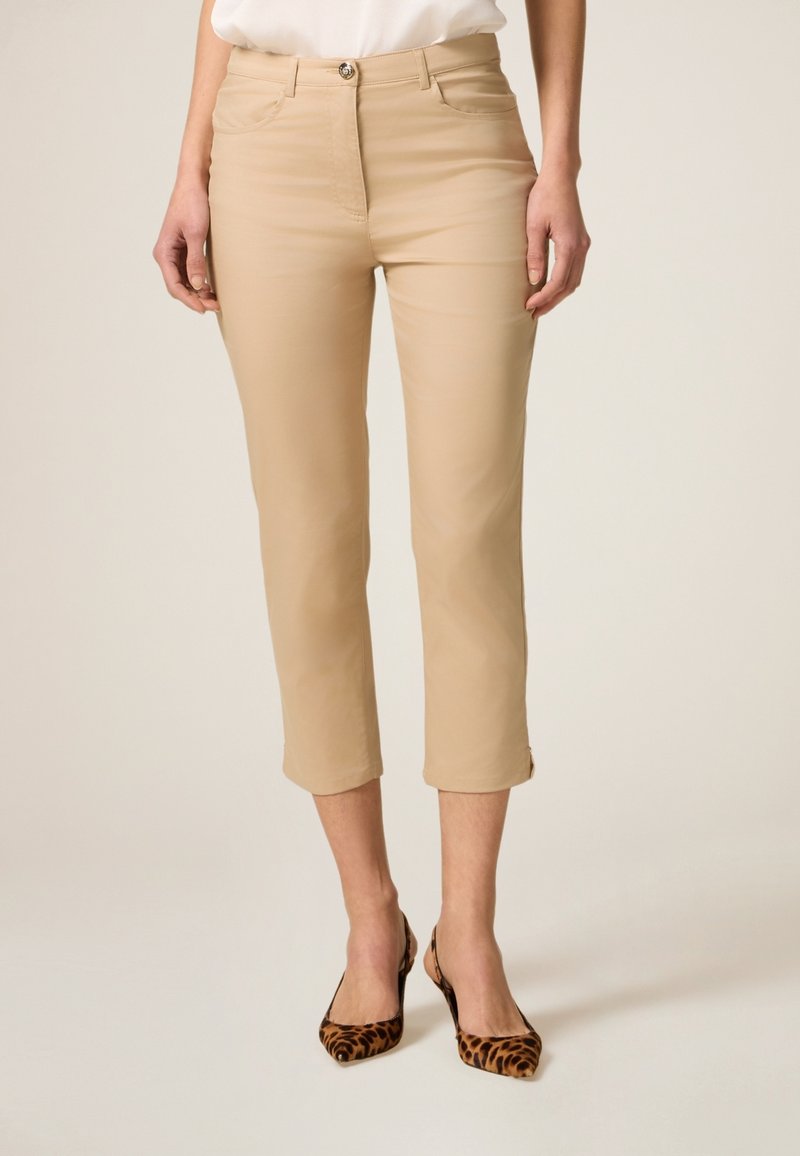 Beige cropped broeken met voorzakken en een slim fit, voorzien van een knoopsluiting en een gladde textuur. Gecombineerd met dierenprint hakken.