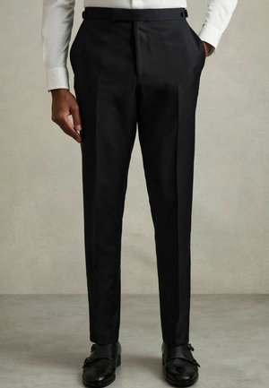 Black tailored trousers with a slim fit, made of smooth fabric, featuring front pleats and side pockets, paired with black dress shoes.
