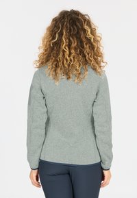 Harmaa fleece-takki, jossa on teksturoitu pinta ja pitkät hihat, tummalla kaula-aukolla ja koristeellisilla olkaosuilla.