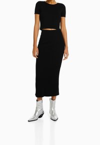 Svart ribbad tvådelad set bestående av en croppad topp och midi kjol, ihop med blanka silver cowboystövlar med tjock klack.