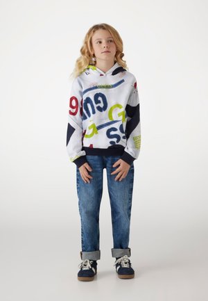 Felpa con cappuccio con design grafico multicolore; presenta testo rosso, blu e verde, polsini a coste; abbinata a jeans in denim arrotolati e sneakers.