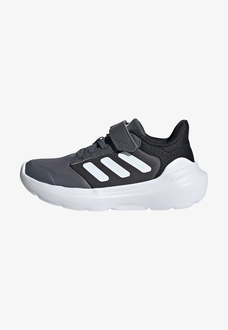 Baskets de sport noires et grises avec un dessus en mesh, trois rayures blanches en accent, et une cheville rembourrée. Elles présentent une épaisse semelle en caoutchouc blanche.