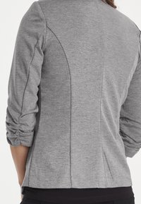Gray pullover jacket with three-quarter sleeves, featuring gathered details at the sleeves and a smooth texture. Simple design with seams visible.