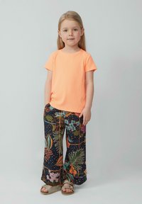 Feloranje T-shirt met korte mouwen en ribbelstructuur, gecombineerd met marineblauwe wijde bloemenbroek. De outfit heeft levendige kleuren en een relaxte pasvorm.