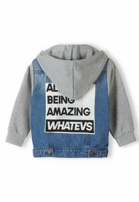 Chaqueta de sudadera gris de mezclilla con un estampado gráfico que presenta el texto "TODOS SON INCREÍBLES WHATEVS" en la parte posterior. Cierre de botones en la parte inferior.