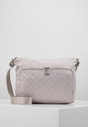 Hellbeige Umhängetasche mit sich wiederholendem Kreis-Muster, vordere Reißverschlusstasche, Doppelreißverschluss und verstellbarem Schulterriemen auf weißer Oberfläche.