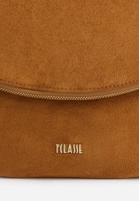 Borsa a tracolla in suede marrone con patta arrotondata, cerniera dorata e logo in rilievo. Texture morbida e design minimalista con colore uniforme.