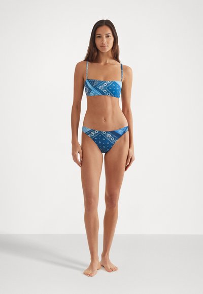 Blue patterned bikini set with a bandeau top and low-rise briefs, featuring intricate designs in lighter blues and white accents.