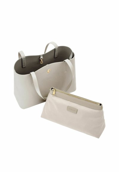 Svetlo bež torba z dvema ročajema in usklajeno torbico z zadrgo, ki je postavljena spredaj na belem ozadju.