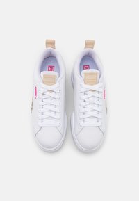 Białe sneakersy z gładkiego syntetycznego materiału, płaskimi białymi sznurówkami, beżowymi akcentami i różowym logo po boku. Okrągły czubek i niski profil.