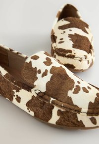 Bruine en witte koeienprint loafers gemaakt van zacht, gestructureerd materiaal met een ronde neus en gestikte details; flexibele rubberen zool.