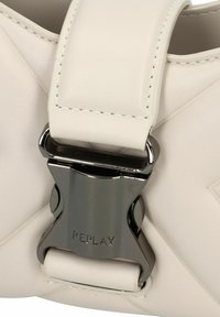 Witte leren handtas met een gequilt ontwerp, een glanzende zilveren sluiting en contrasterende stiksels, met een zichtbare merklabel.