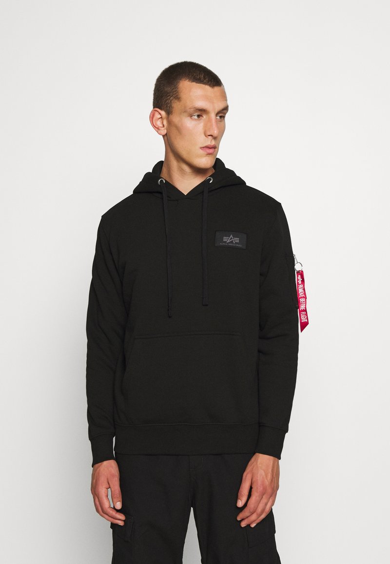 Sudadera negra de mezcla de algodón. Cuenta con un bolsillo tipo canguro, capucha ajustable con cordón y un parche de marca en el pecho. Acento de etiqueta roja.