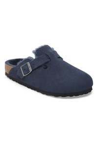Marineblaue Clogs aus weichem Wildleder, mit einer Schnalle, flauschigem Futter und einer strukturierten Gummisohle. Offenes Design für ein einfaches Hineinschlüpfen.