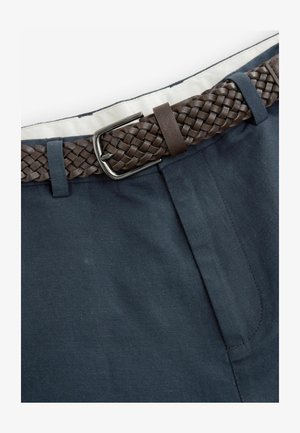 Sötétkék nadrág lapos elülső résszel, fonott barna bőr övvel és fémből készült csattal. Simává varrott anyag, tiszta kivitelezés.