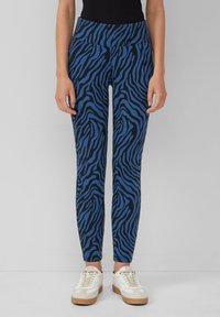Blauwe en zwarte zebra print leggings met een hoge tailleband, gekenmerkt door een gladde stof en een strakke pasvorm, gecombineerd met witte sneakers.