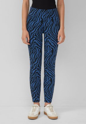 Blauwe en zwarte zebra print leggings met een hoge tailleband, gekenmerkt door een gladde stof en een strakke pasvorm, gecombineerd met witte sneakers.