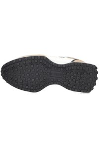 Zwarte rubberen zool met een gestructureerde grip; heeft verhoogde cirkelvormige patronen en een glad middenstuk in beige en witte materialen.